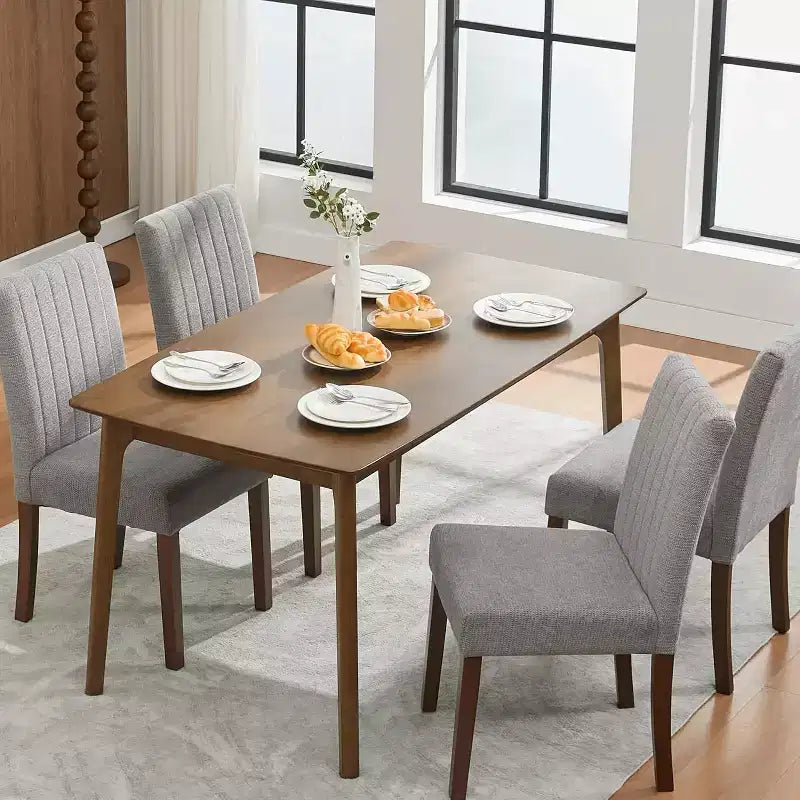 Un set di quattro sedie da pranzo con morbidi cuscini, decorate con bottoni, dotate di gambe in legno e sedute morbide, adatte per sale da pranzo cucine grigie